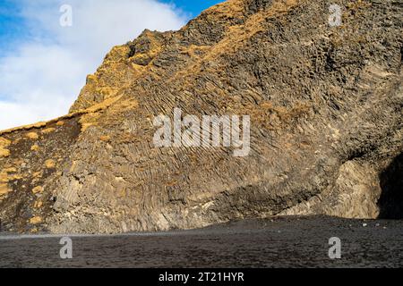 Una vista pittoresca di una grotta di basalto su una spiaggia di sabbia nera in Islanda, che si affaccia sul mare Foto Stock