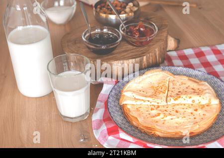 Dolci pancake rotondi sdraiati su un piatto rotondo accanto alla marmellata Foto Stock