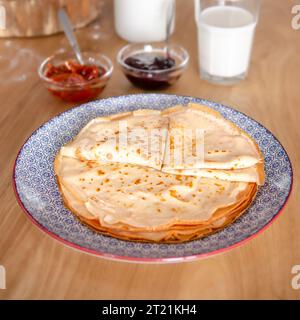 Dolci pancake rotondi sdraiati su un piatto rotondo accanto alla marmellata Foto Stock