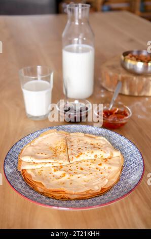 Dolci pancake rotondi sdraiati su un piatto rotondo accanto alla marmellata Foto Stock