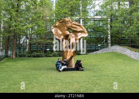 People sitting Around fortuna, una scultura in bronzo di Helaine Blumenfeld nel Jubilee Park, Canary Wharf, Londra Foto Stock