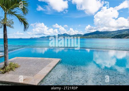 Piscina infinity con vista mare sull'isola tropicale. Foto Stock