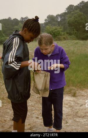 Due giovani ragazze guardano in un sacchetto di lumache hanno catturato con le reti in acqua al Chincoteague National Wildlife Refuge, situato in Virginia. Soggetti: Giovani; rifugi faunistici; connettere le persone con la natura; bambini. Località: Virginia. Fish and Wildlife Service Site: RISERVA NATURALE NAZIONALE DI CHINCOTEAGUE. . 1998 - 2011. Foto Stock