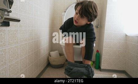 Un bambino adorabile seduto sul sedile del WC. bambino che fa i suoi bisogni igienici Foto Stock