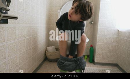 Un bambino adorabile seduto sul sedile del WC. bambino che fa i suoi bisogni igienici Foto Stock