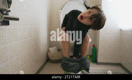 Un bambino adorabile seduto sul sedile del WC. bambino che fa i suoi bisogni igienici Foto Stock