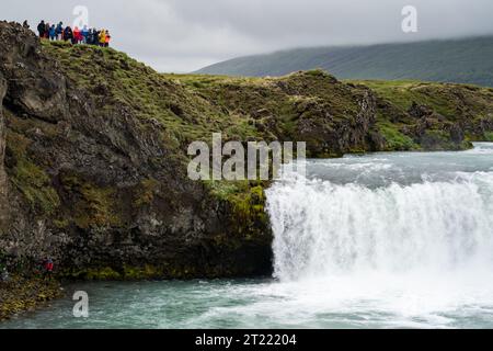 Godafoss, Islanda - 4 luglio 2023: I turisti ammirano la famosa cascata di Godafoss da un punto panoramico superiore Foto Stock