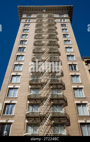 Basso angolo di alto edificio residenziale a più piani con pareti in mattoni e fuochi d'artificio contro il cielo blu senza nuvole nelle soleggiate giornate di San Francisco Foto Stock