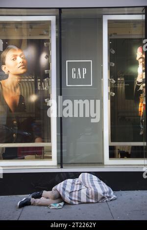 Un senzatetto dormiva sul marciapiede di fronte a un negozio GAP nella zona di Times Square a Manhattan, New York. Foto Stock