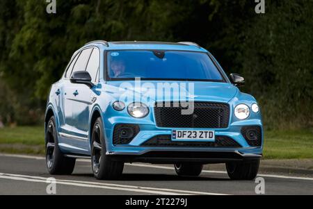 Bicester, Oxon., Regno Unito - 8 ottobre 2023: 2023 blu Bentley Bentayga V8 auto d'epoca che guida su una strada di campagna inglese. Foto Stock