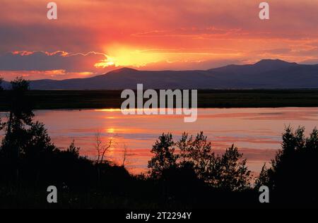 Un tramonto sul Red Rock Lakes National Wildlife Refuge, Montana, con le Centennial Mountains come sfondo spettacolare. Il rifugio offre ai visitatori tranquille vedute panoramiche delle zone umide circostanti. Ubicazione: Montana. Foto Stock