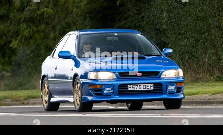 Bicester, Oxon., UK - 8 ottobre 2023: 1997 auto d'epoca blu Subaru che guida su una strada di campagna inglese. Foto Stock