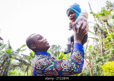 Un padre africano gioca con il figlio appena nato e lo solleva nel cielo Foto Stock