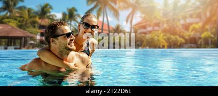 coppia sorridente che si diverte insieme nella piscina del resort. vacanze estive, viaggi brevi. striscione con spazio per la copia Foto Stock