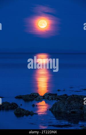 La super luna (una luna blu) del 30/8/2023 che si innalza sull'isola di Arran vista dalla penisola di Kintyre, Scozia, Regno Unito Foto Stock