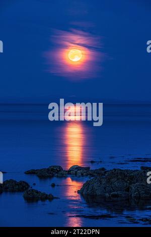 La super luna (una luna blu) del 30/8/2023 che si innalza sull'isola di Arran vista dalla penisola di Kintyre, Scozia, Regno Unito Foto Stock