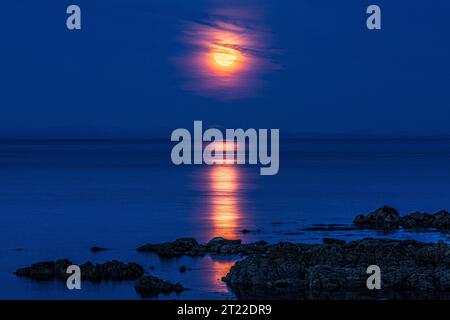 La super luna (una luna blu) del 30/8/2023 che si innalza sull'isola di Arran vista dalla penisola di Kintyre, Scozia, Regno Unito Foto Stock