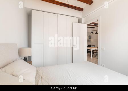 Grande guardaroba e morbido letto nella camera da letto minimalista bianca Foto Stock