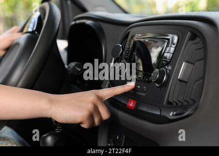 Scelta della radio preferita. Donna che preme il pulsante sull'audio del veicolo in auto, primo piano Foto Stock