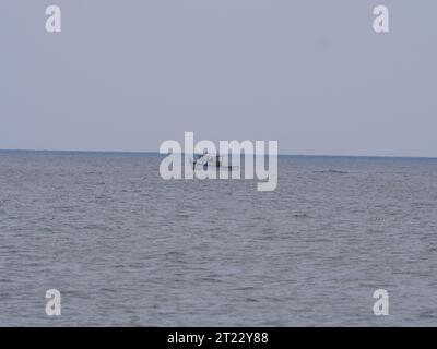 Un piccolo motoscafo naviga sul mare di fronte alla spiaggia della Cornovaglia a Porthcurno Foto Stock