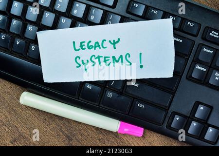 Concetto di sistemi legacy! Scrivere sulle note adesive isolate sul tavolo di legno. Foto Stock