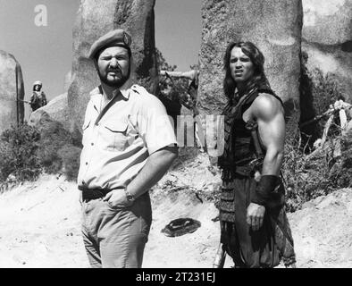 Il regista JOHN MILIUS e ARNOLD SCHWARZENEGGER sul set di CONAN IL BARBARO personaggio del 1982 creato da ROBERT E. HOWARD Costume Design JOHN BLOOMFIELD Music BASIL POLEDOURIS Universal Pictures Foto Stock