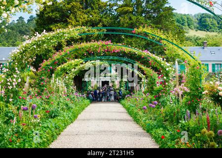 Archi di rosa e colorati fiori estivi confinano a Giverny, il giardino del pittore impressionista francese Claude Monet, Normandia, Francia settentrionale Foto Stock