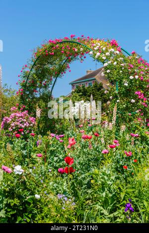Archi di rosa e colorati fiori estivi confinano a Giverny, il giardino del pittore impressionista francese Claude Monet, Normandia, Francia settentrionale Foto Stock