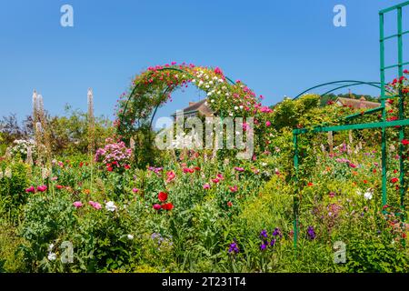 Archi di rosa e colorati fiori estivi confinano a Giverny, il giardino del pittore impressionista francese Claude Monet, Normandia, Francia settentrionale Foto Stock