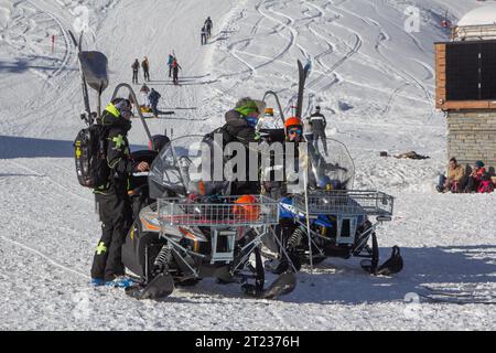 Una pattuglia di sci a Tignes, in Francia, con le loro sofisticate motoslitte, si preparano mentre gli sciatori di fondo si muovono dietro di loro su una pista da sci. Foto Stock