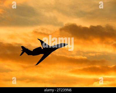 Silhouette di un jet privato che decolla contro un cielo invernale al tramonto. Niente persone. Copia spazio. Foto Stock