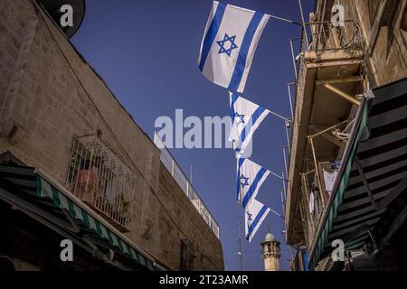 Le bandiere di Israele sono sulle strade della città vecchia di Gerusalemme con il minareto della moschea sullo sfondo, in Israele. Foto Stock