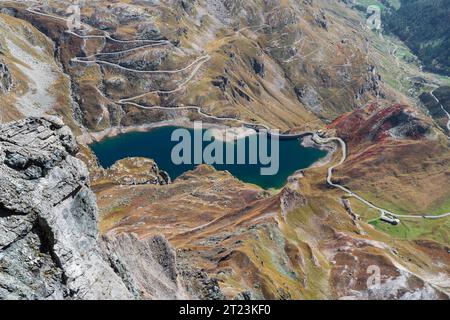 Lago dell'Agnel e diga, strada tortuosa per il passo Nivolet (Ceresole reale, Valle dell'Orco) Parco Nazionale del Gran Paradiso. colorato paesaggio montano in autunno Foto Stock