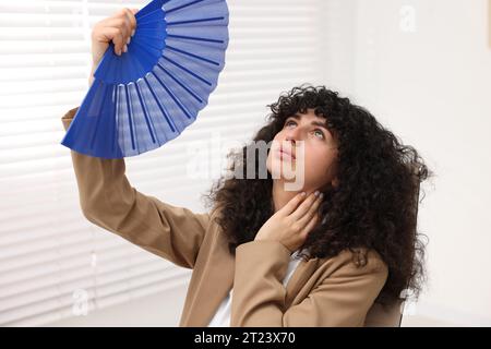 Una giovane donna d'affari che si diverte con la mano blu per rinfrescarsi in ufficio Foto Stock