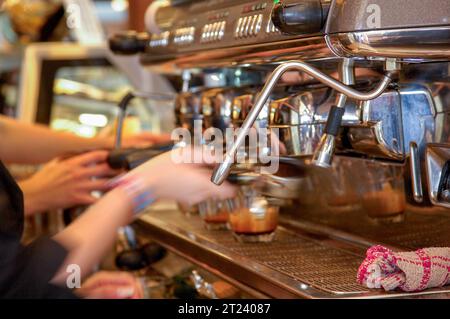 due baristi preparano il caffè con una macchina espresso in un caffè o in una caffetteria Foto Stock