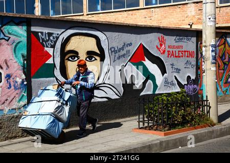 Un uomo spinge un carro davanti a un murale che mostra sostegno per una Palestina libera e chiede la fine dell'olocausto palestinese, del distretto di Miraflores, di la Paz, Bolivia. La foto è stata scattata nel settembre 2018. Foto Stock