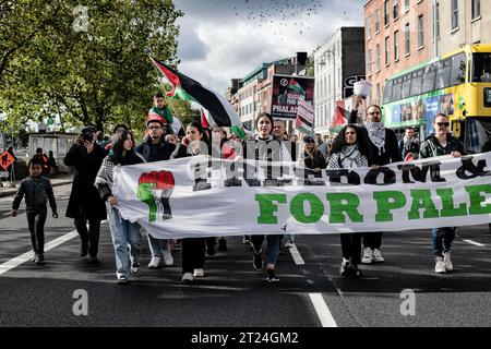 Dublino, Irlanda. 14 ottobre 2023. I manifestanti con uno striscione, bandiere e cartelli marciano attraverso Dublino verso l'ambasciata israeliana durante la manifestazione. Sabato 14 ottobre si è svolta una terza giornata di proteste a Dublino in solidarietà con il popolo palestinese. Migliaia di persone hanno marciato da o'Connell Street attraverso la città fino all'ambasciata israeliana dove i relatori della comunità palestinese e siriana hanno parlato delle loro esperienze e delle notizie recenti ricevute dai familiari e dagli amici di Gaza, nonché dai membri dei gruppi I.P.S.C. (campagna di solidarietà della Palestina in Irlanda) e dalla gente Foto Stock