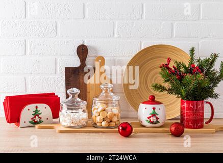 Moderno concetto di cucina casalinga. Rami di abete rosso, taglieri in legno, piatti con un motivo di Capodanno. Vista frontale del ripiano della cucina Foto Stock