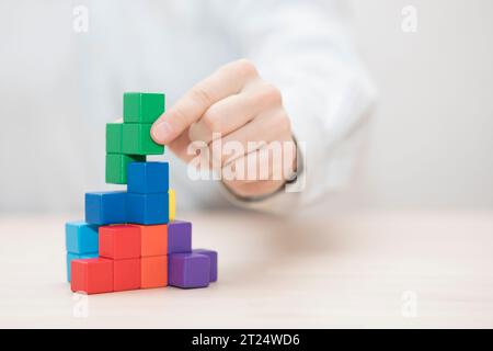 Man mano colorati di impilamento dei blocchi di legno. Business development concept Foto Stock