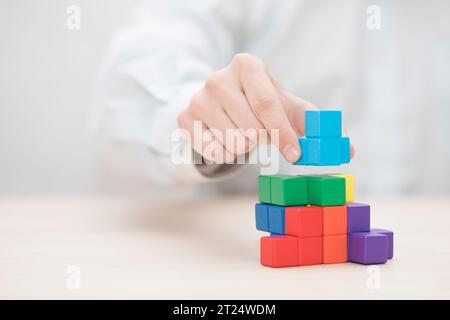 Man mano colorati di impilamento dei blocchi di legno. Business development concept Foto Stock