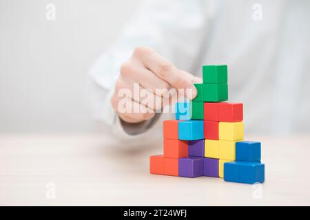 Man mano colorati di impilamento dei blocchi di legno. Business development concept Foto Stock