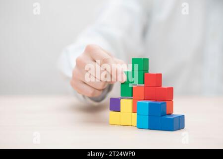 Man mano colorati di impilamento dei blocchi di legno. Business development concept Foto Stock