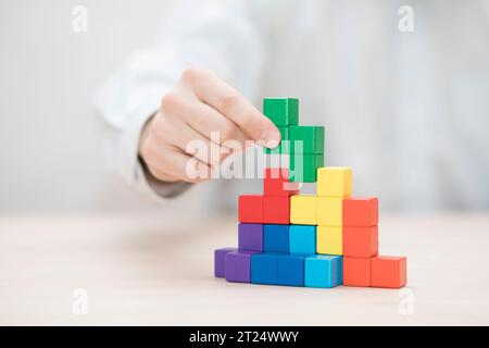 Man mano colorati di impilamento dei blocchi di legno. Business development concept Foto Stock