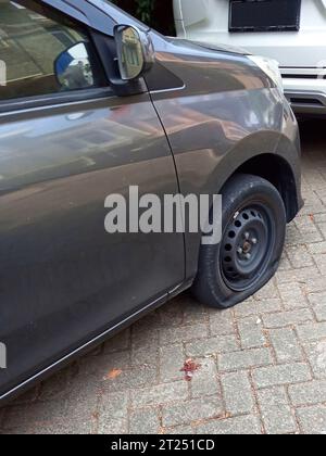 Vista ravvicinata dello pneumatico di un'auto sgonfio, ruota forata Foto Stock