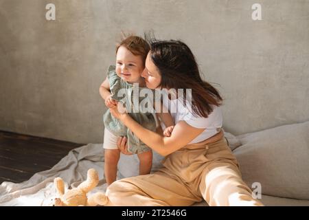 Donna sorridente seduta sul pavimento a giocare con sua figlia Foto Stock