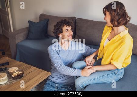Ritratto di una giovane coppia felice che si tiene per mano e sorride. Foto Stock