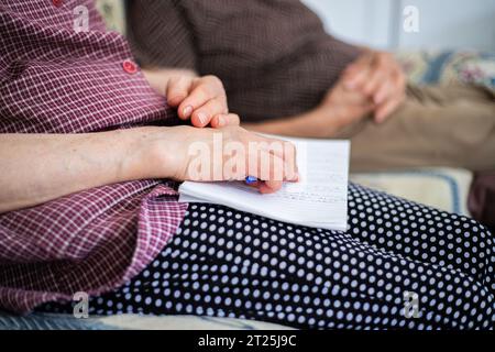 Due persone anziane sedute sul divano si rilassarono e con le mani sullo stomaco sotto forma di riposo. Foto Stock