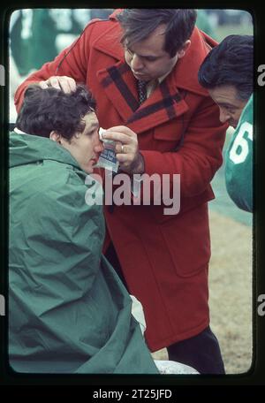 New York Jets ortopedico e medico di squadra Dr. Robert Grossman controlla la salute di un giocatore. Ai margini di una partita di football del 1978 allo Shea Stadium di New York. Grossman faceva parte dello staff dell'Institute of Sports Medicine and Athletic Trauma. L'atleta è John Roman, il lineman dei Jets. Foto Stock