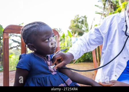 Un medico ascolta il battito cardiaco di una bambina con uno stetoscopio in Africa. Foto Stock