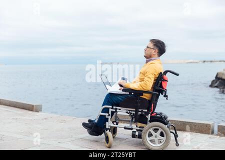 un uomo che passeggia in riva al mare con un portatile Foto Stock